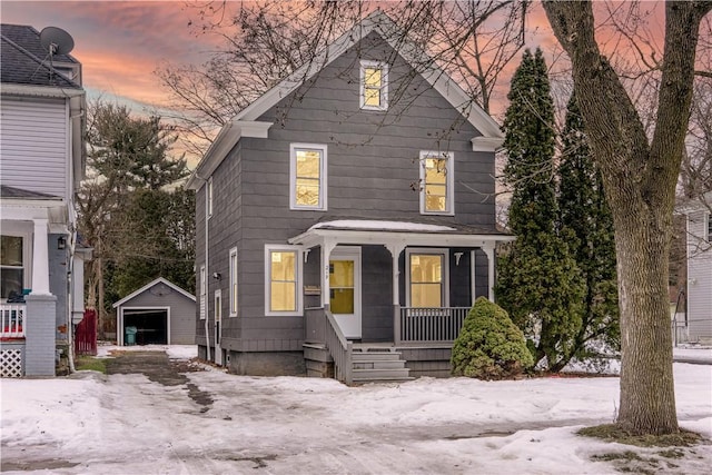 american foursquare style home featuring a porch, an outbuilding, driveway, and a garage