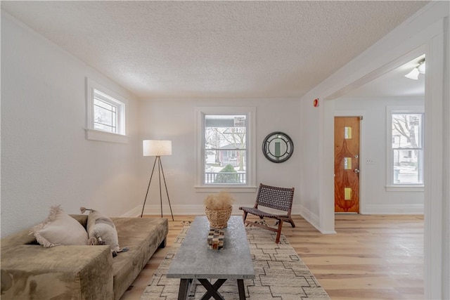 living room with baseboards, a textured ceiling, and light wood finished floors