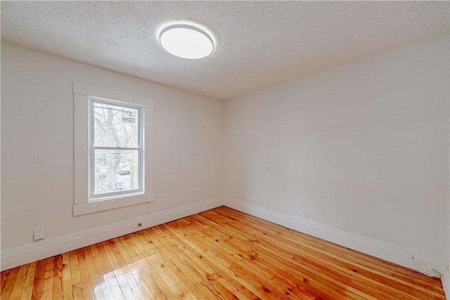 unfurnished room featuring baseboards, a textured ceiling, and light wood finished floors