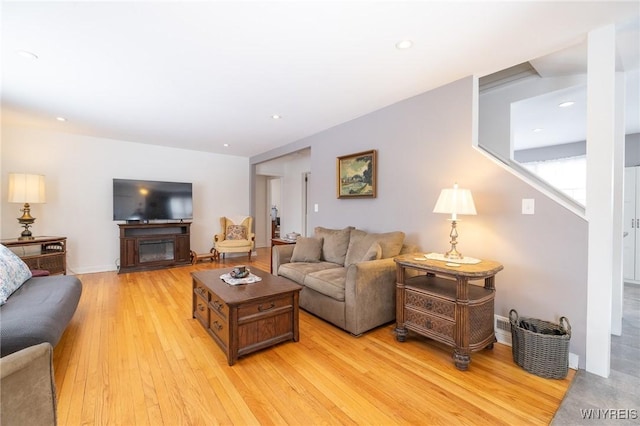 living area featuring light wood-style floors, a glass covered fireplace, and recessed lighting