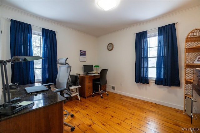 office featuring baseboards, light wood-type flooring, visible vents, and crown molding