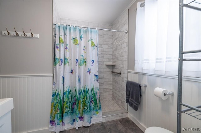 bathroom featuring a wainscoted wall and a tile shower