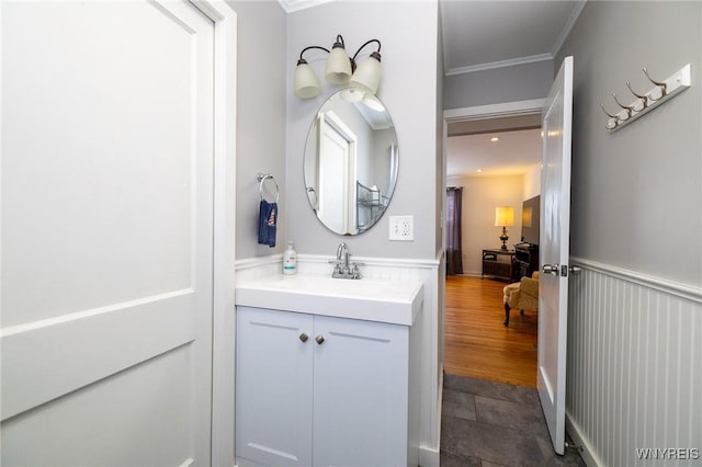 bathroom featuring ornamental molding, a wainscoted wall, vanity, and wood finished floors