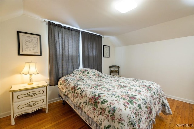 bedroom with baseboards, vaulted ceiling, and wood finished floors