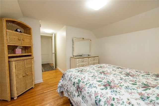 bedroom with light wood-style floors, vaulted ceiling, and baseboards