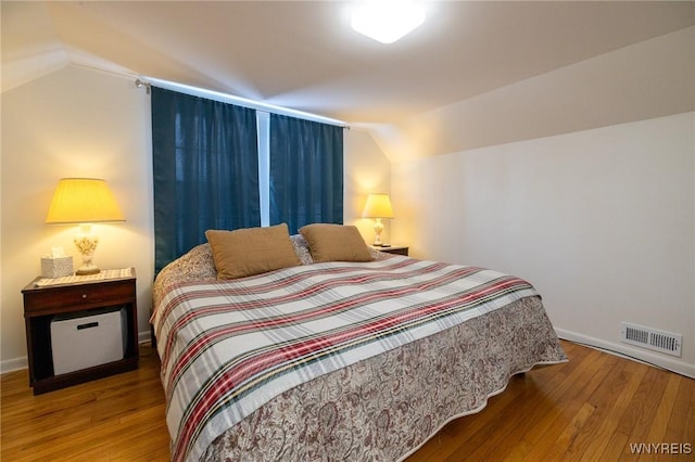 bedroom with lofted ceiling, visible vents, and wood finished floors