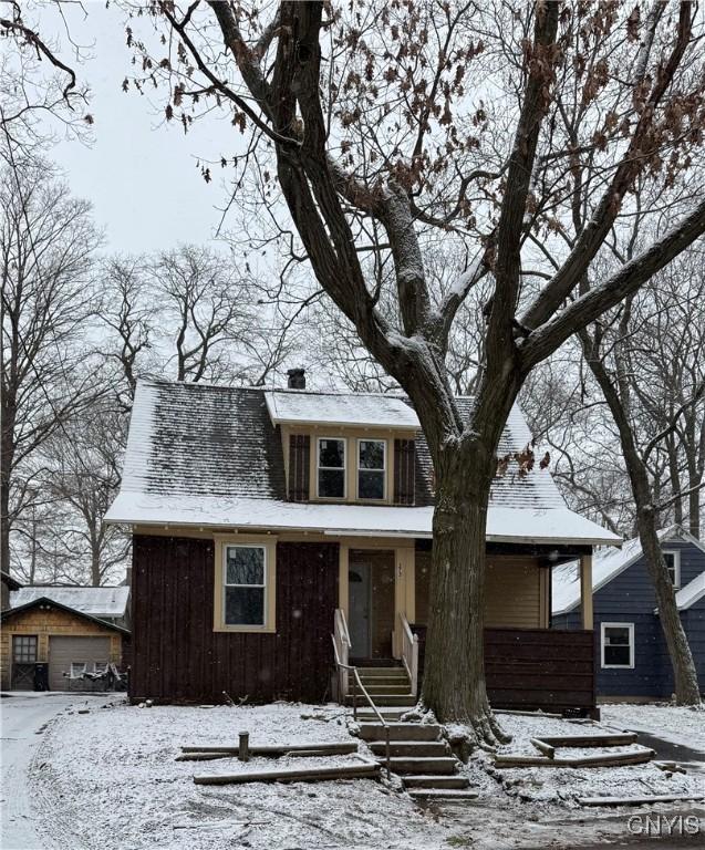 view of front facade with board and batten siding, a detached garage, and a chimney