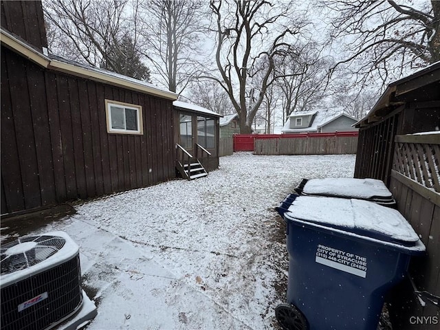 yard covered in snow with fence and central AC unit