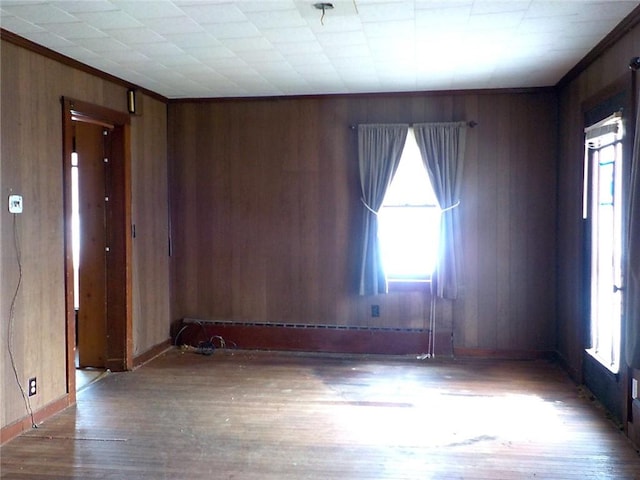 unfurnished room featuring hardwood / wood-style floors, wood walls, and a wealth of natural light