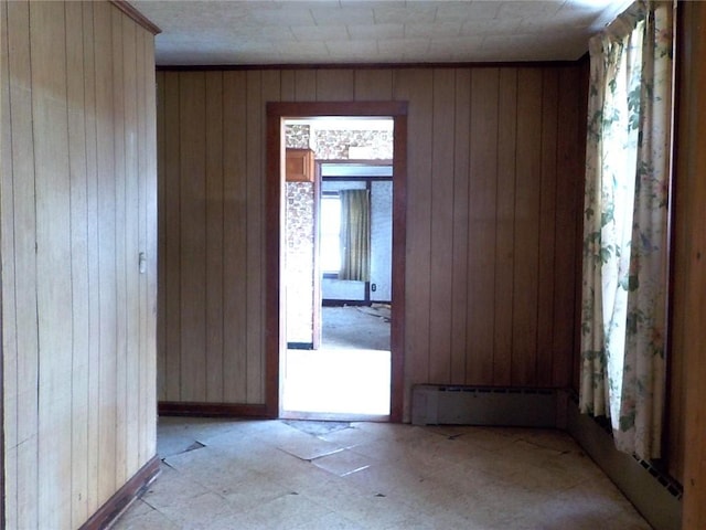 unfurnished room featuring a baseboard heating unit and wood walls