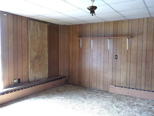 unfurnished room featuring a drop ceiling and wooden walls