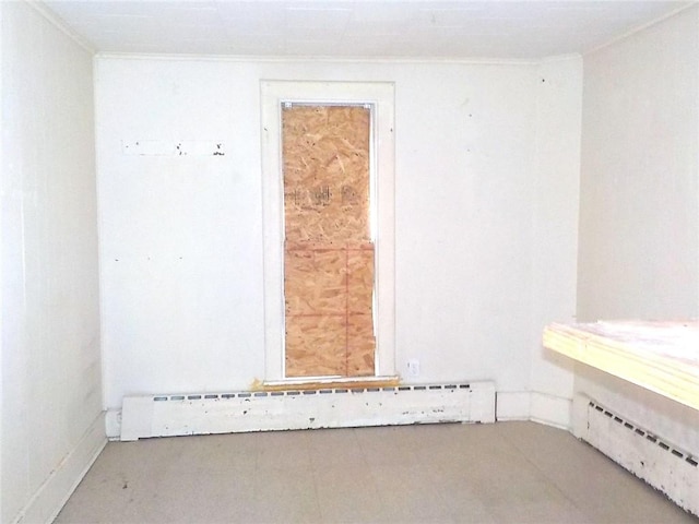 spare room featuring a baseboard heating unit and crown molding