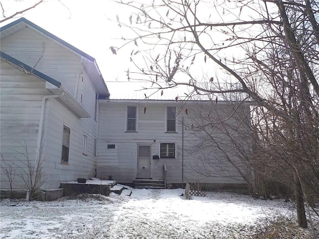 snow covered back of property featuring entry steps