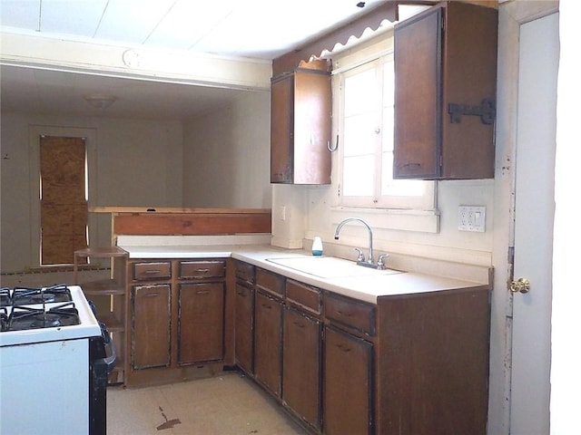 kitchen featuring light countertops, white gas range, and a sink