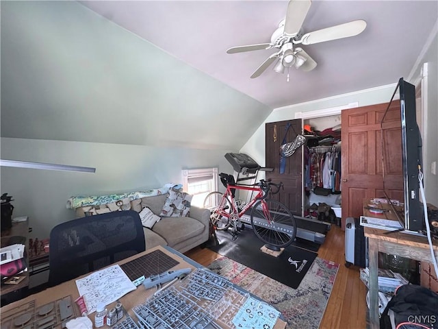 exercise area featuring a ceiling fan, vaulted ceiling, and wood finished floors