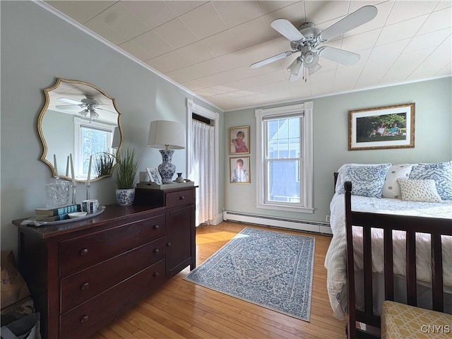 bedroom featuring light wood finished floors, a baseboard radiator, ceiling fan, and crown molding