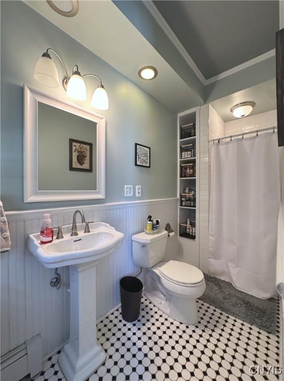 full bath with toilet, a baseboard heating unit, a shower with shower curtain, and wainscoting