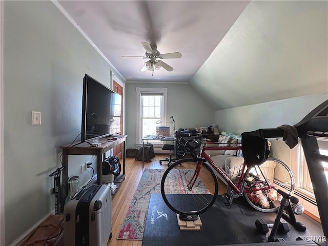 interior space with lofted ceiling, light wood-style floors, ornamental molding, a ceiling fan, and baseboards