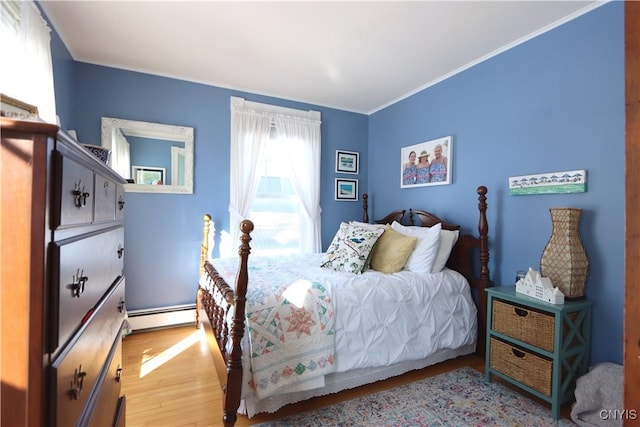 bedroom featuring light wood-style floors, a baseboard heating unit, and crown molding