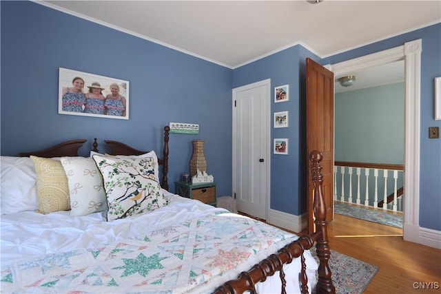 bedroom featuring ornamental molding, wood finished floors, and baseboards