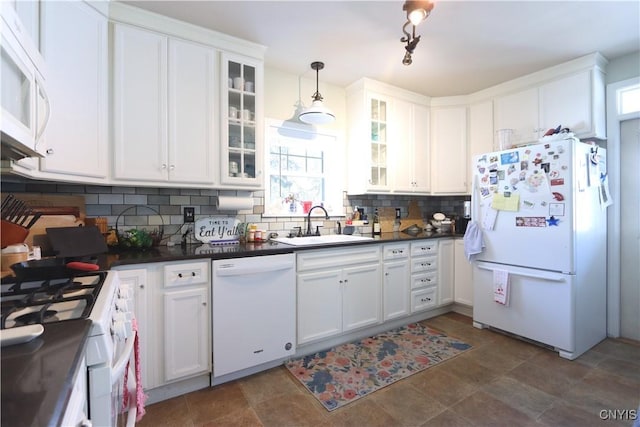 kitchen with white appliances, white cabinets, decorative backsplash, dark countertops, and a sink