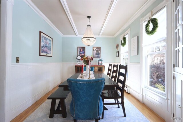 dining space with light wood-style flooring, crown molding, and a notable chandelier