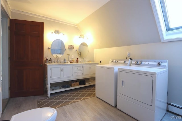 washroom featuring laundry area, a skylight, a baseboard radiator, washer and dryer, and light wood-style floors