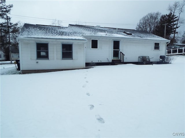 snow covered house featuring a shingled roof and entry steps