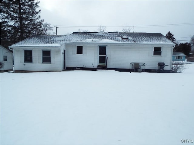 snow covered house featuring a shingled roof and entry steps