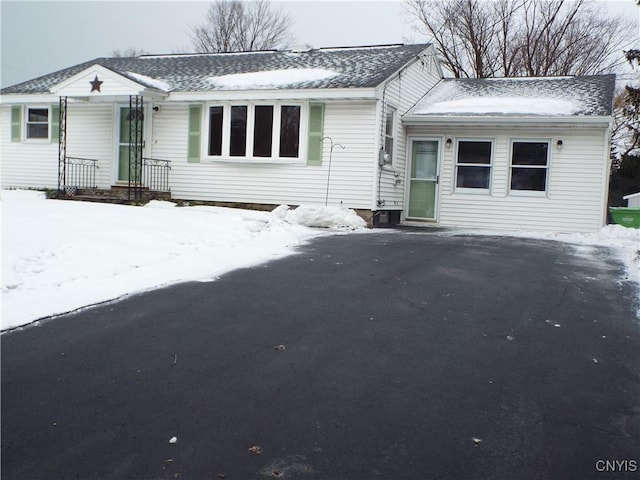 single story home featuring aphalt driveway and roof with shingles