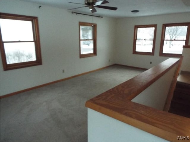 carpeted empty room with a ceiling fan and baseboards