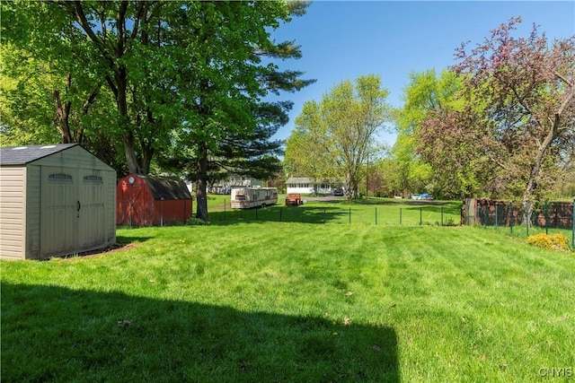 view of yard featuring fence, an outdoor structure, and a storage unit