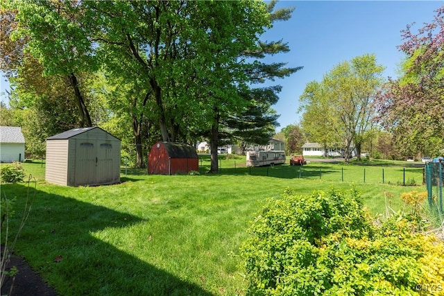 view of yard with fence, an outdoor structure, and a storage unit