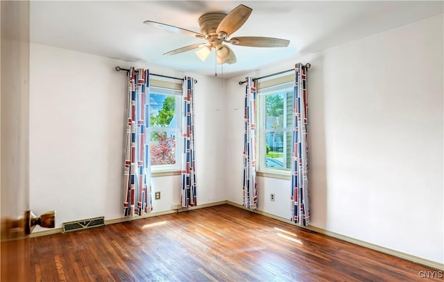 spare room with a wealth of natural light, wood finished floors, visible vents, and a ceiling fan