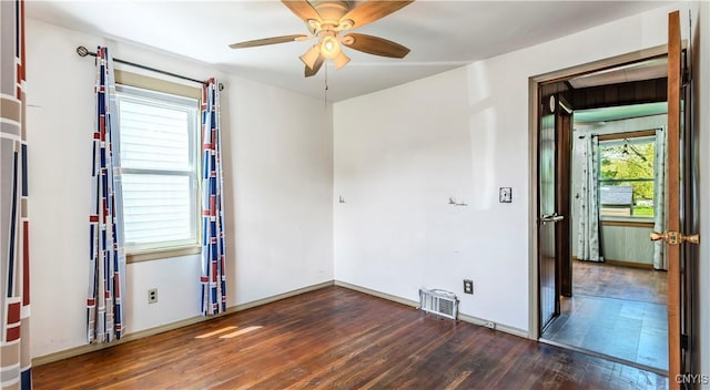 empty room with baseboards, wood-type flooring, visible vents, and a ceiling fan