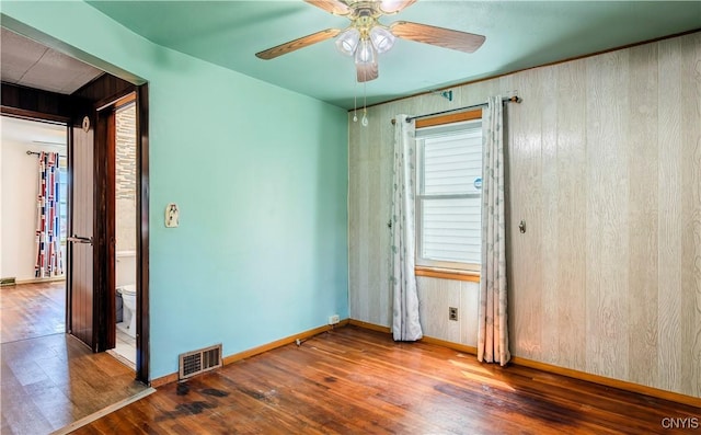 spare room featuring visible vents, ceiling fan, baseboards, and wood finished floors