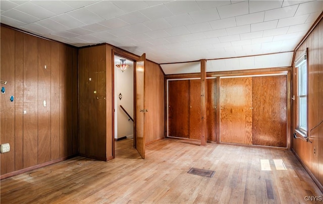 spare room with wood walls, wood finished floors, and visible vents