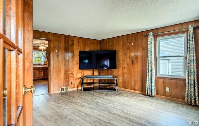 living room featuring a textured ceiling, wood finished floors, visible vents, and baseboards