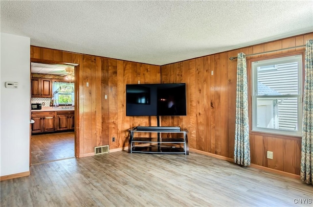 living room featuring a textured ceiling, wood finished floors, visible vents, and baseboards