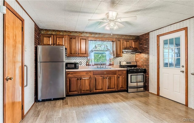 kitchen featuring under cabinet range hood, appliances with stainless steel finishes, and brown cabinetry