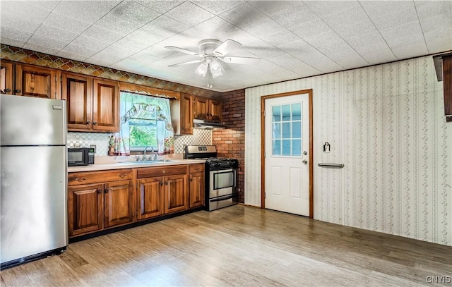 kitchen featuring brown cabinets, light wood-style flooring, stainless steel appliances, and a sink