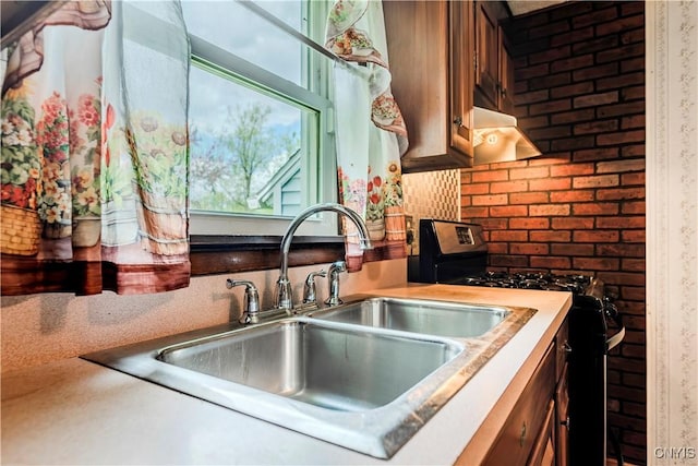 kitchen with light countertops, exhaust hood, gas range oven, and a sink