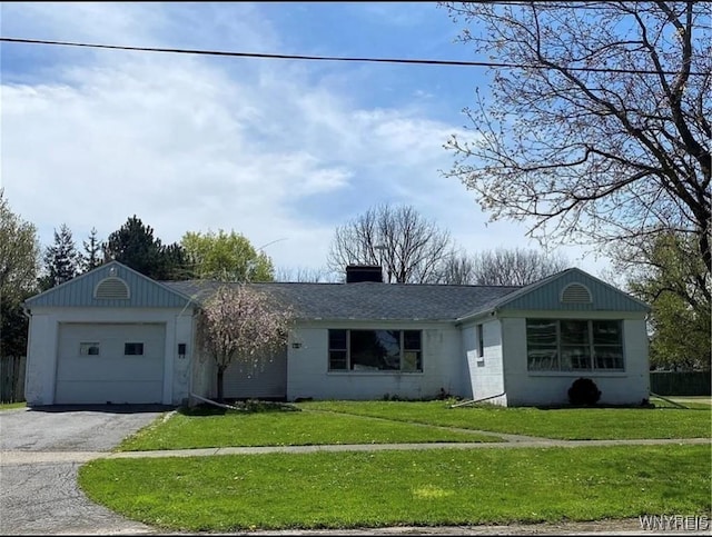 ranch-style home featuring an attached garage, a chimney, aphalt driveway, and a front yard