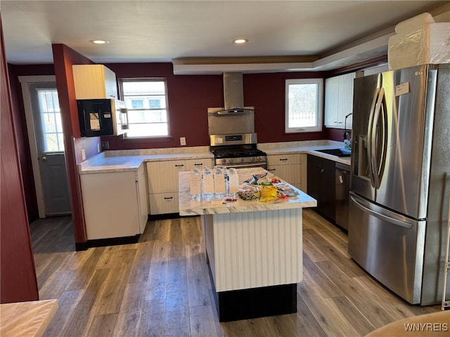 kitchen with stainless steel appliances, light countertops, plenty of natural light, and wall chimney range hood