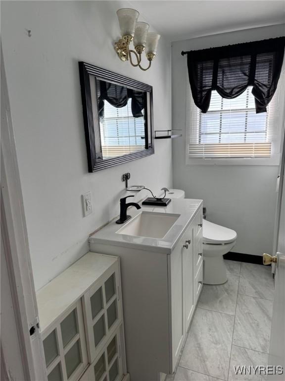 bathroom featuring vanity, toilet, and an inviting chandelier