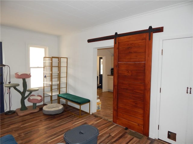 sitting room featuring ornamental molding, a barn door, and wood finished floors