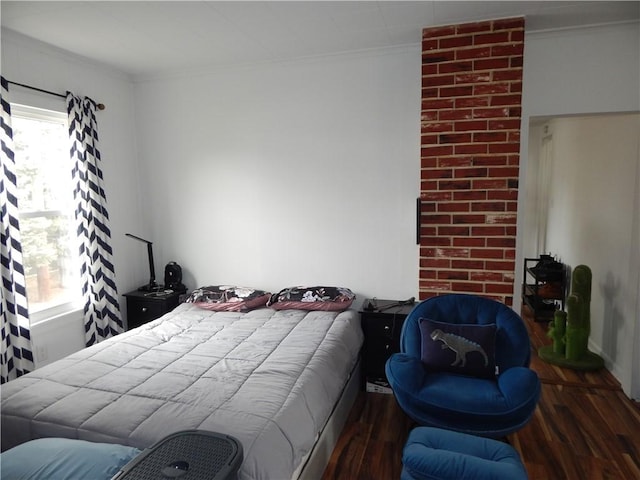 bedroom with ornamental molding and wood finished floors