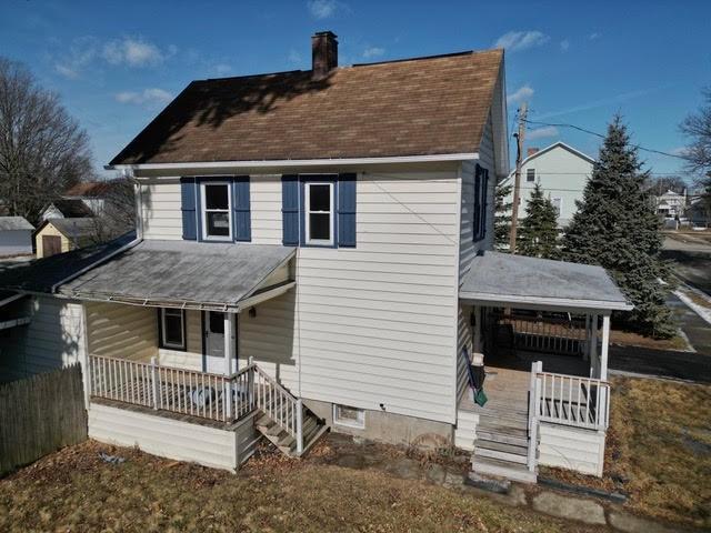 rear view of house with a porch, a chimney, and a shingled roof