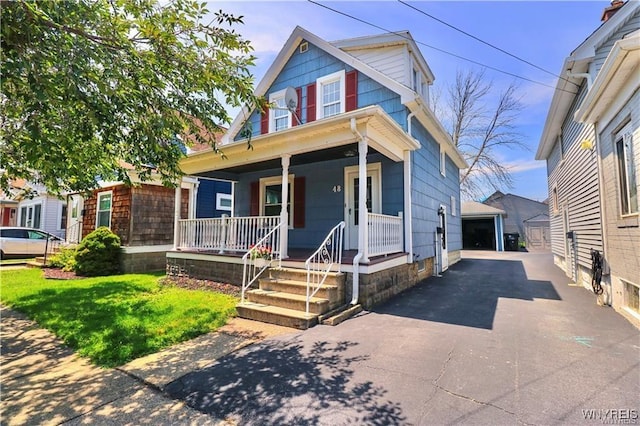 view of front of property featuring covered porch, a detached garage, and an outbuilding