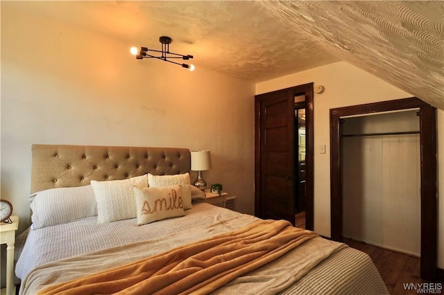 bedroom featuring lofted ceiling, a textured ceiling, and wood finished floors